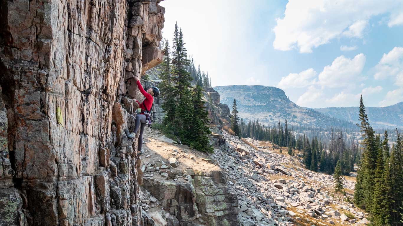A White Pine Touring guide climbs on a rock climbing route in the Uinta Mountains, UT