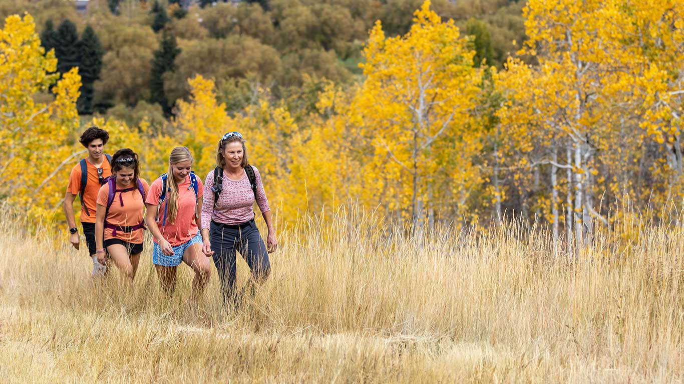 White Pine guide leads a hiking tour through trees in fall colors of yellow and red near Park City, UT.