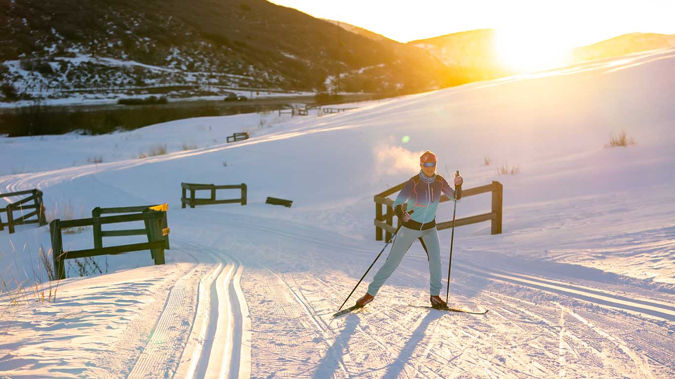 White Pine Touring guide skate skis on the Nordic track with the sunrise behind them in Park City, UT.