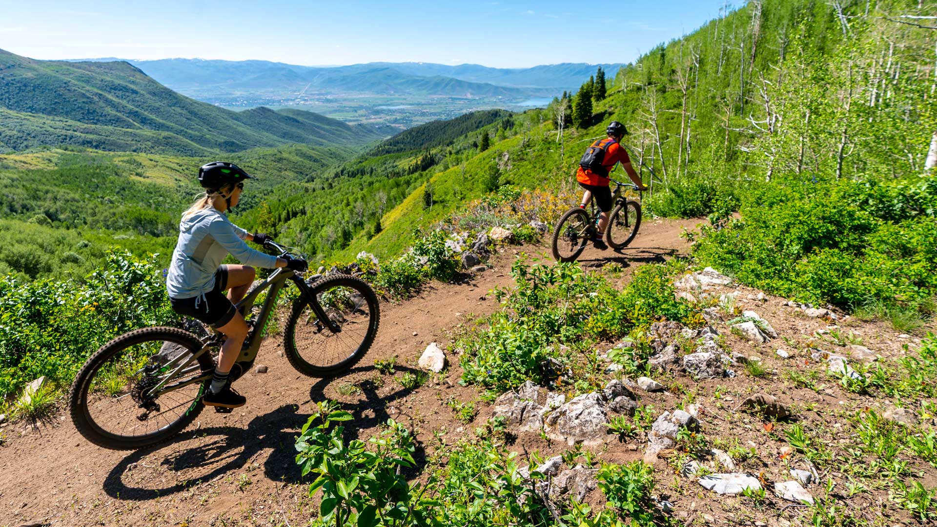 A rider and a guide cruise a Park City, UT trail on electric mountain bikes