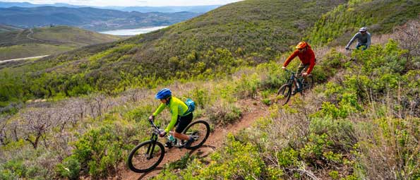 Two riders and an instructor mountain bike on a trail in Park City, UT