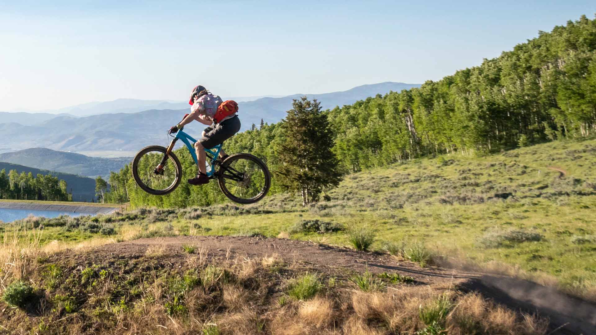 A mountian biker catches air off a jump on a Deer Valley trail in Park City, UT