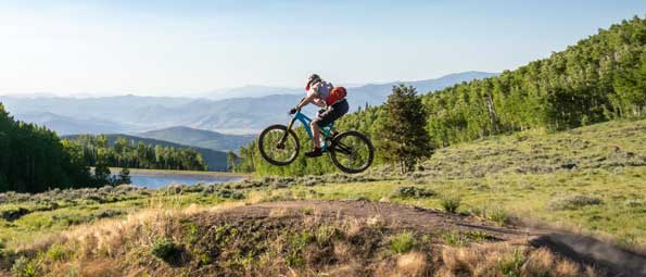 A mountian biker catches air off a jump on a Deer Valley trail in Park City, UT