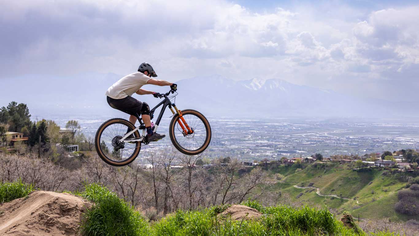 A mountain biker airs off a jump in the hills above Salt Lake City, UT