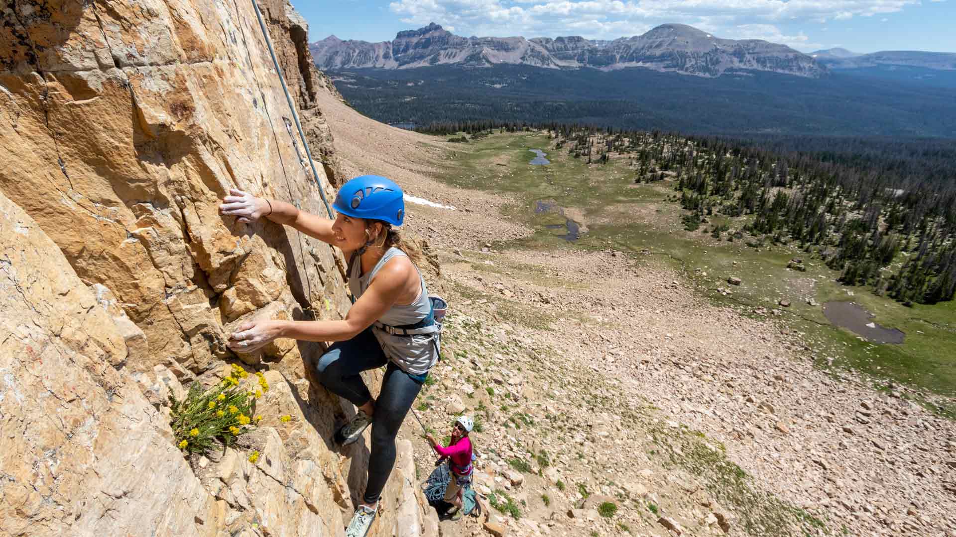 A guide belays as a climber ascends a rock face in the Uinta mountains outside Park City, UT