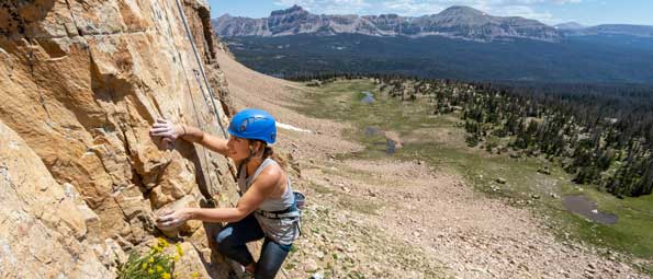 A guide belays as a climber ascends a rock face in the Uinta mountains outside Park City, UT